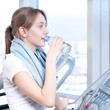 Woman at the gym exercising. Run on on a machine and drink water