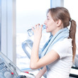 Woman at the gym exercising. Run on on a machine and drink water