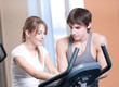 Train on machine in a gym assisted by personal instructor