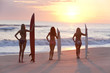 Women Surfers In Bikinis With Surfboards At Sunset Beach