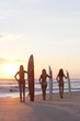 Women Surfers In Bikinis With Surfboards At Sunset Beach