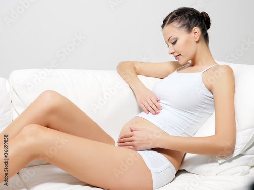 Photo: Happy pregnant woman sitting on sofa Happy pregnant woman sitting on sofa