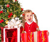 Child giving gift box by christmas tree.