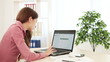 Business woman working on a computer turns at camera.