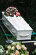 White coffin with pink sympathy flowers