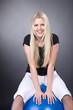 Junge blonde Frau sitzt auf Sport Ball und lacht