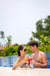 An young and attractive couple having drinks by the pool