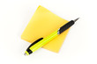 Post-it o pósit y bolígrafo amarillo en fondo blanco.