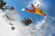 Snowboarder jumping against blue sky