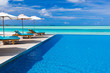 Deck chairs and infinity pool over tropical lagoon Deck chairs and infinity pool over tropical lagoon