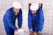 tradesman teaching his apprentice how to read a blueprint