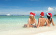 Photo: Happy friends in santa hats on the beach Happy friends in santa hats on the beach