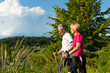 Happy mature or senior couple doing Nordic walking in summer
