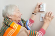 Photo: Senior woman adjusting her thermostat Senior woman adjusting her thermostat