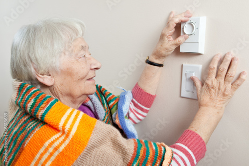 Photo: Senior woman adjusting her thermostat Senior woman adjusting her thermostat