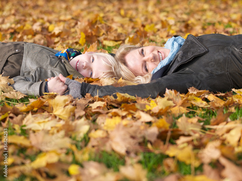 Photo: Mother and daughter enjoy autumn while lying in leaves Mother and daughter enjoy autumn while lying in leaves