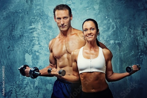 Photo: Athletic man and woman with a dumbells. Athletic man and woman with a dumbells.