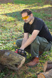 Man cutting tree trunk with electric saw