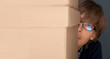 Portrait of young man holding on box against grey wall. He is st