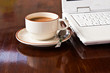 Cup of coffee beside laptop