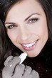 A young woman applying lip balm, smiling