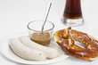 Frische Breze, Weißwurst, Senf und Bier auf weißem Hintergrund