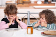 Grumpy children at a table with pancakes