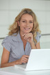 Blond woman sat at desk with laptop computer Blond woman sat at desk with laptop computer