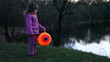 little girl hold one colorful ball from paper near lake