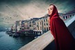 Beautifiul woman in red cloak on a bridge.