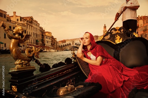 Photo: Beautifiul woman in red cloak riding on gandola Beautifiul woman in red cloak riding on gandola