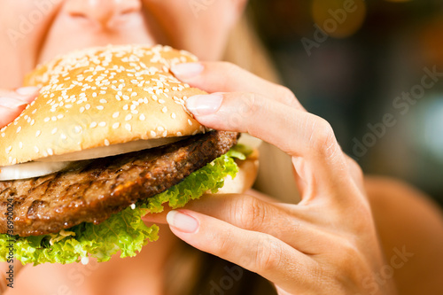 Foto: Frau im Restaurant isst Hamburger Frau im Restaurant isst Hamburger