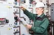 Electrician working in white helmet with blueprints in hands