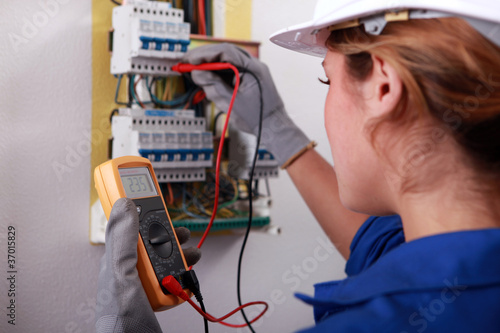 Photo: Female electrician taking reading from fuse box Female electrician taking reading from fuse box