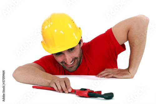 Photo: Man struggling to reach a pipe wrench Man struggling to reach a pipe wrench
