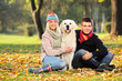 Smiling young man and woman hugging a labrador retreiver dog