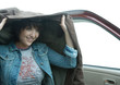Woman getting out of car, holding up jacket over head