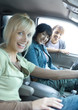 Two women sitting in car, third women looking through car window