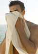 Man drying face with towel, sea in background