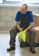 Factory worker sitting on cardboard box