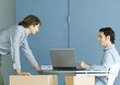 Two male colleagues talking across desk, cardboard boxes in foreground