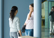 Photo: Two young women standing together near cardboard box, one using cell phone and holding laptop Two young women standing together near cardboard box, one using cell phone and holding laptop