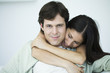 Couple embracing, man smiling at camera, woman looking down
