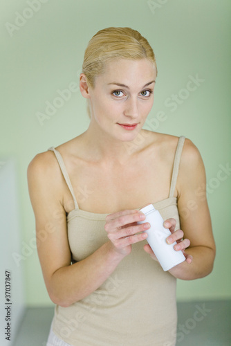 Photo: Mother holding bottle of baby powder, smiling at camera Mother holding bottle of baby powder, smiling at camera