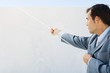 Businessman standing beside wall, pulling rope hanging over edge