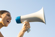 Woman shouting into megaphone, low angle view, cropped