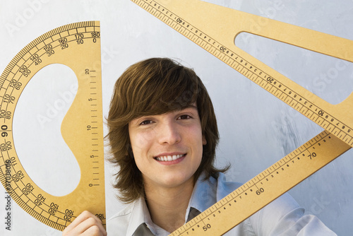 Photo: Young man holding various measuring instruments, smiling at camera Young man holding various measuring instruments, smiling at camera