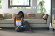 Young woman sitting on living room floor reading book