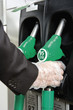 At gas pump with gloved hand removing nozzle