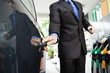 Well-dressed man getting into car after refueling at gas station